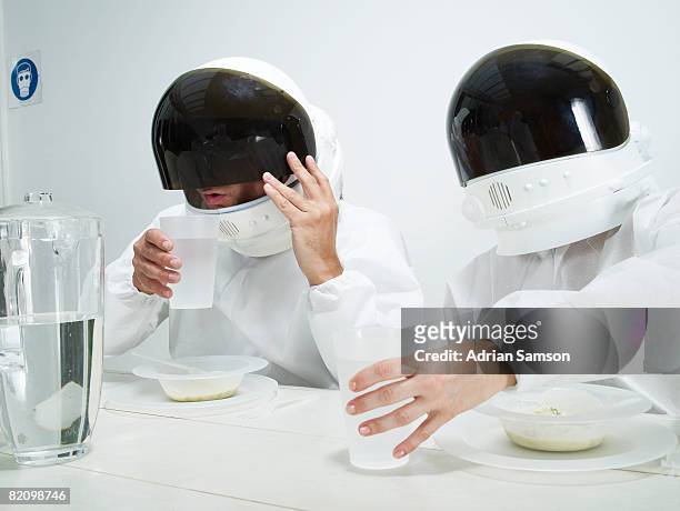 couple in protective suits dining - astronaut helm stock-fotos und bilder