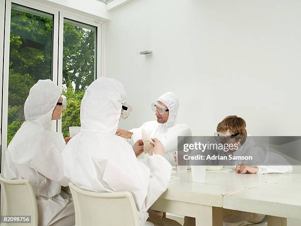family in protective suits dining - schutzanzug stock-fotos und bilder