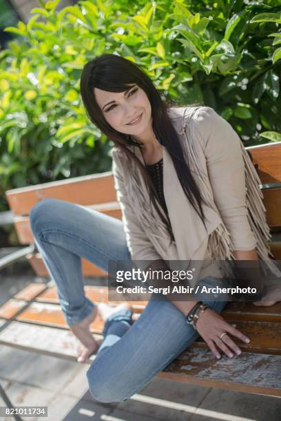 young woman sitting in a bench with some plants behind her - sergi albir imagens e fotografias de stock