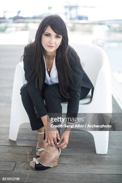 beautiful woman in a black suit adjusting her shoe. - sergi albir imagens e fotografias de stock