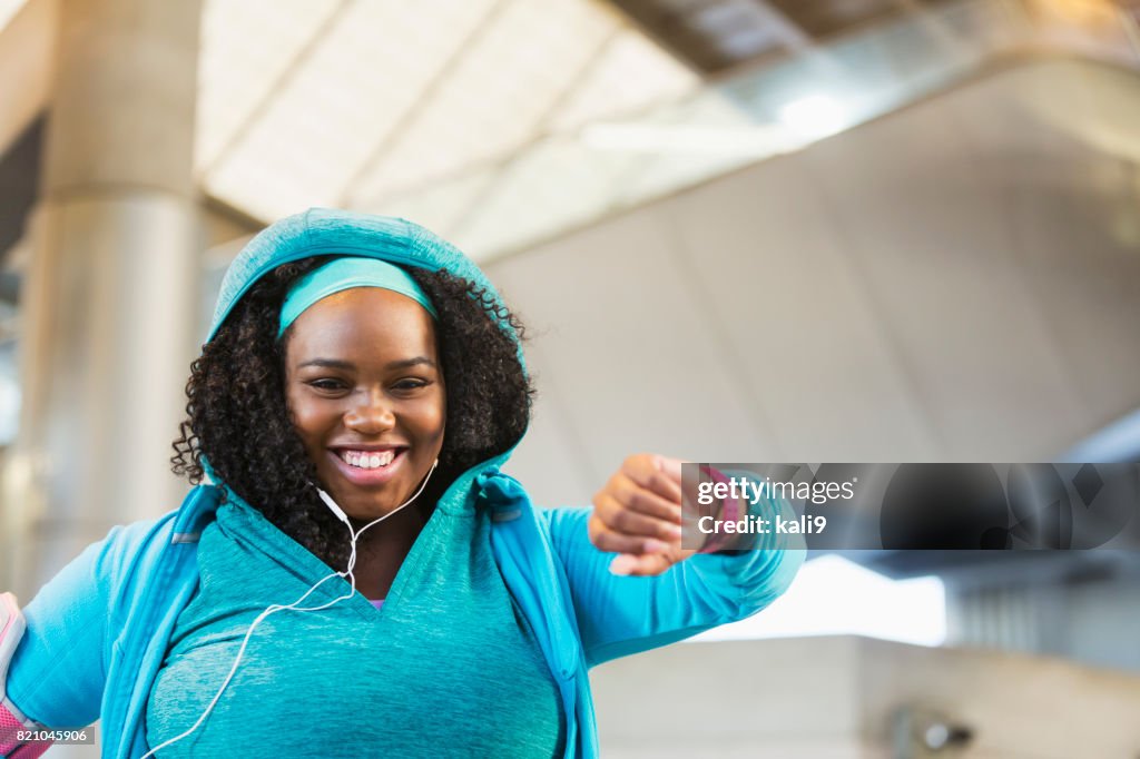 Young black woman exercising, using fitness tracker