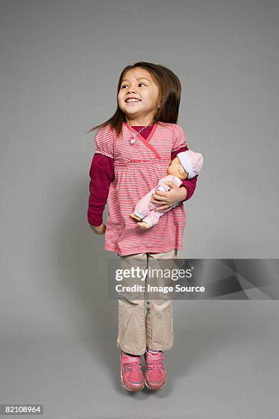 a girl holding a doll - doll fotografías e imágenes de stock