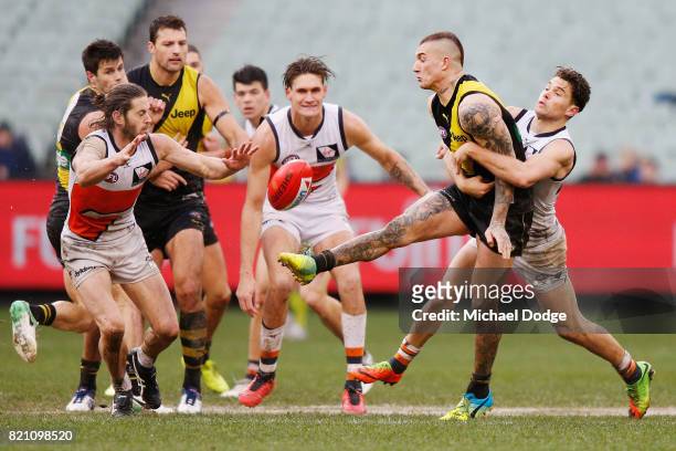 Dustin Martin of the Tigers kicks the ball away from Josh Kelly of the Giants during the round 18 AFL match between the Richmond Tigers and the...