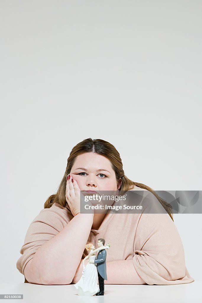 Sullen woman with wedding figurines