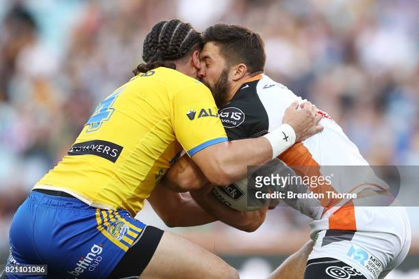 James Tedesco of the Tigers is tackled by Brad Takairangi of the Eels during the round 20 NRL match between the Wests Tigers and the Parramatta Eels...