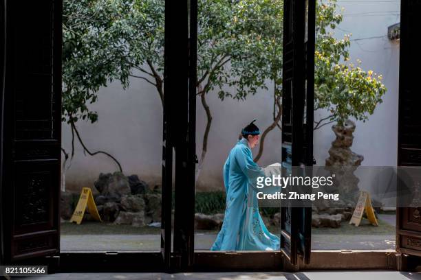 An actor in traditional opera costume walking in the garden of the residence of Ganxi family. Ganxi was a literati in late Qing Dynasty. The...