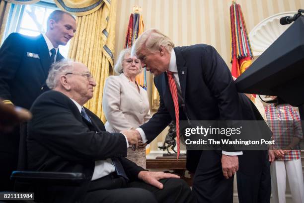 President Donald Trump greets others during a meeting with survivors of the attack on USS Arizona at Pearl Harbor, in the Oval Office of the White...