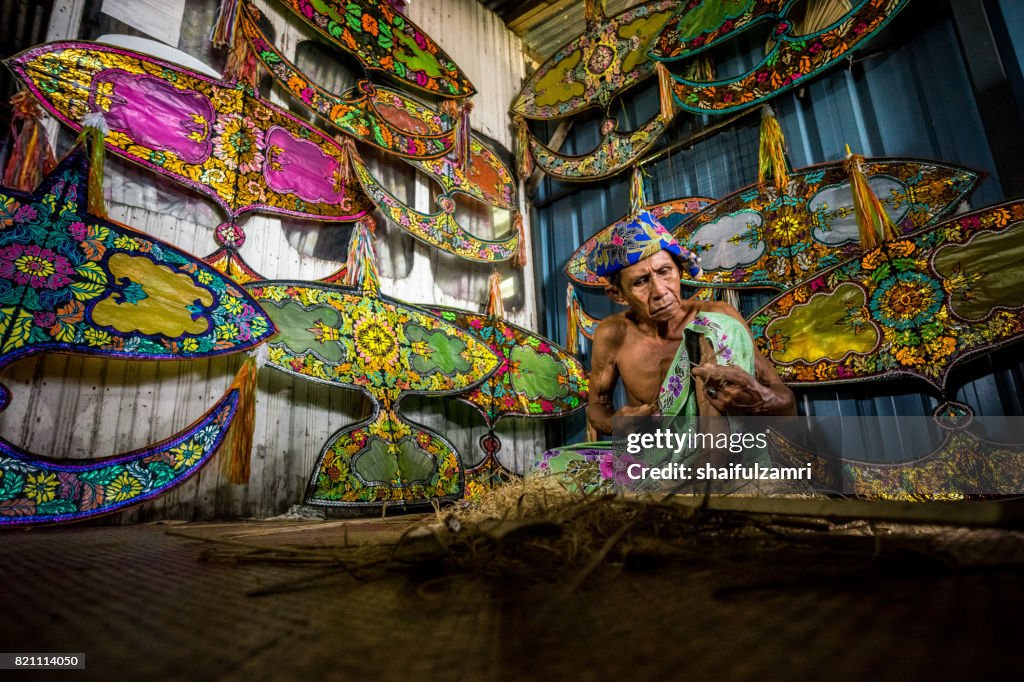 Unidentified man is making the traditional moon kite or locally known as "Wau Bulan" in Kelantan