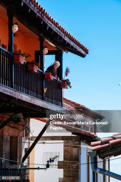 Old woman on a balcony in a traditional house.