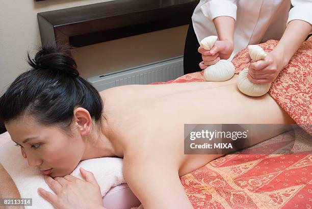 young woman receiving herbal ball massage - massage ball stock pictures, royalty-free photos & images