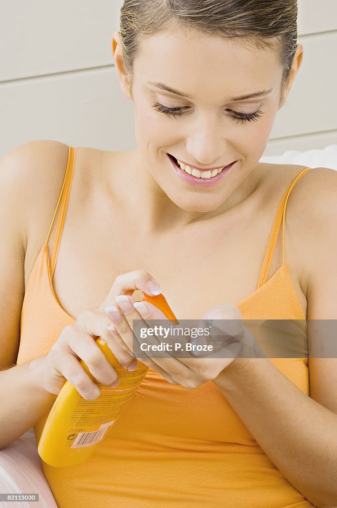 Close-up of a young woman squeezing moisturizer from a bottle