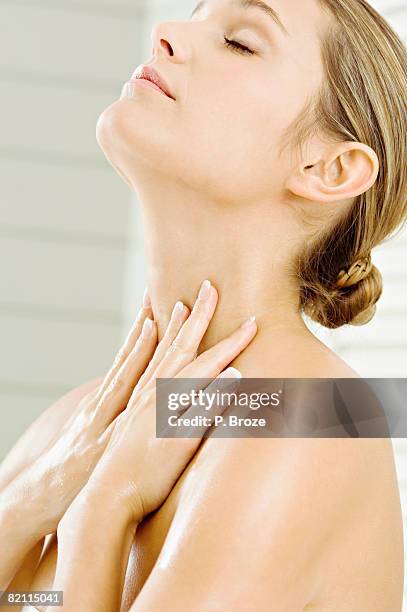 close-up of a young woman applying moisturizer on her neck - woman's neck stock pictures, royalty-free photos & images