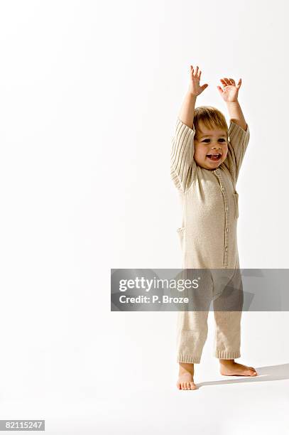 baby boy standing with his arms raised and smiling - babygro stock pictures, royalty-free photos & images