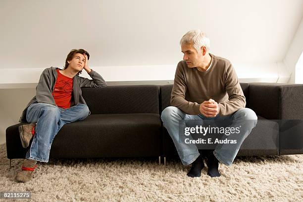 mature man and his son sitting on a couch - men in white socks 個照片及圖片檔