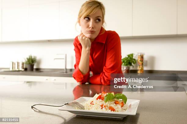 plate of rice in front of a young woman leaning against a kitchen counter - picky eater stockfoto's en -beelden