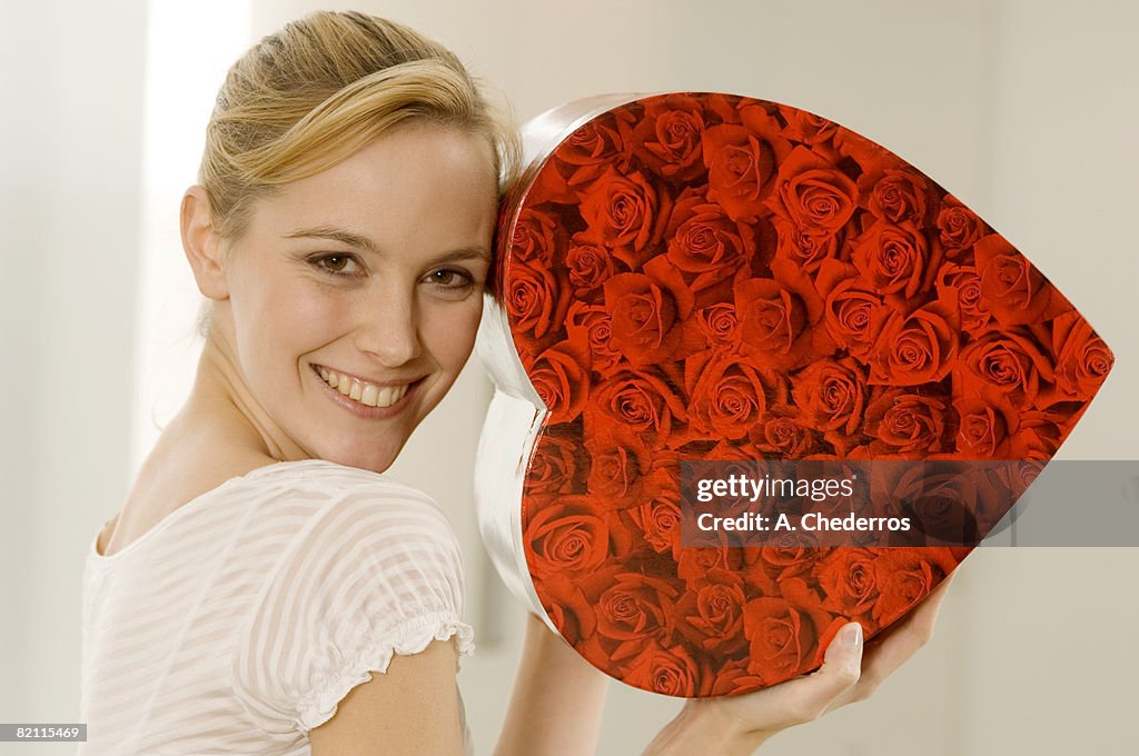 Portrait of a young woman showing a heart shape gift and smiling