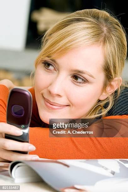 close-up of a young woman using a mobile phone and smiling - feature phone stockfoto's en -beelden