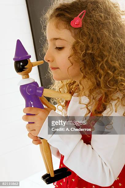 side profile of a girl playing with a toy - pinocchio - fotografias e filmes do acervo