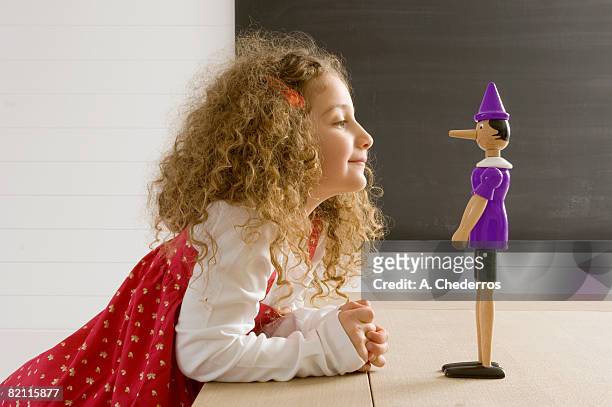 side profile of a girl playing with a toy - lying photos et images de collection