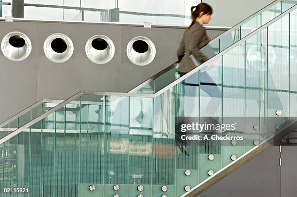 businesswoman carrying a laptop and moving up on a staircase - airport stairs stock pictures, royalty-free photos & images