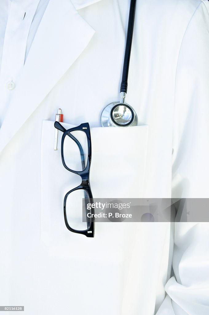 Close-up of eyeglasses and a pen in a lab coat of a doctor