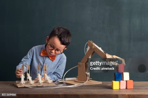 cute child invented robot arm with cardboard. - child inventor stock pictures, royalty-free photos & images