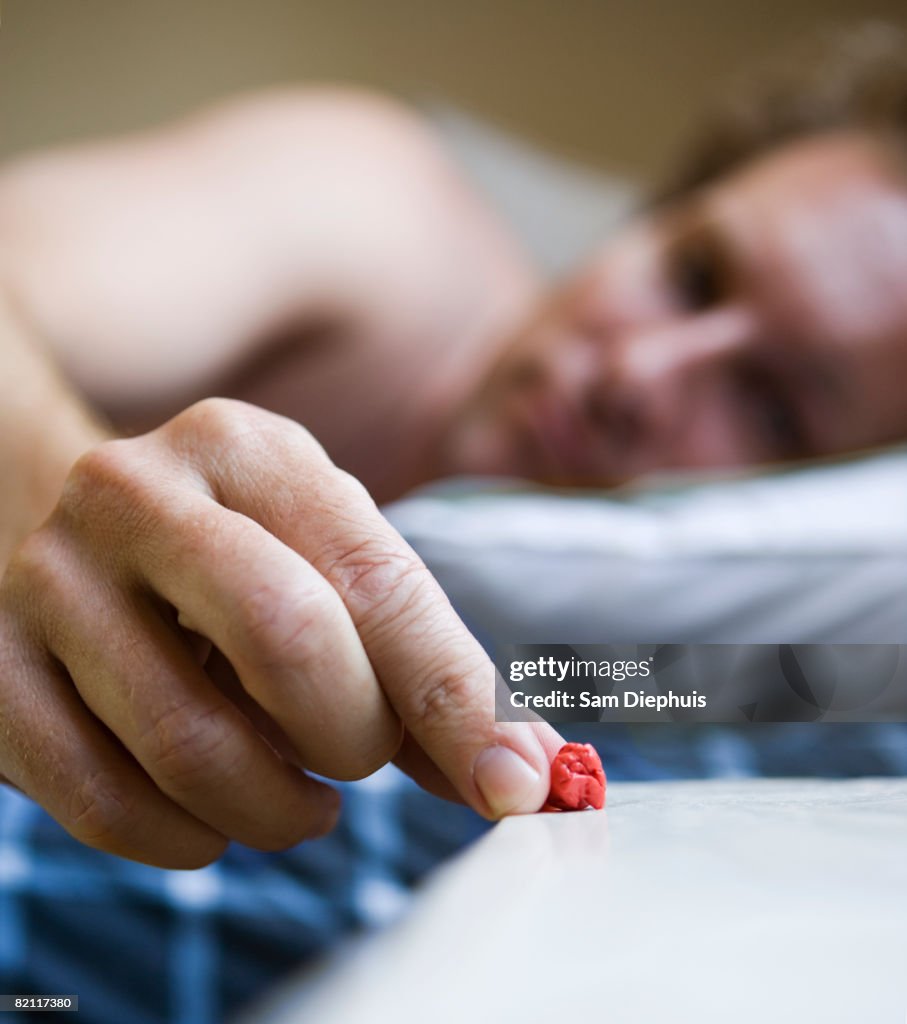 Man putting chewed gum on nightstand, focus on gum