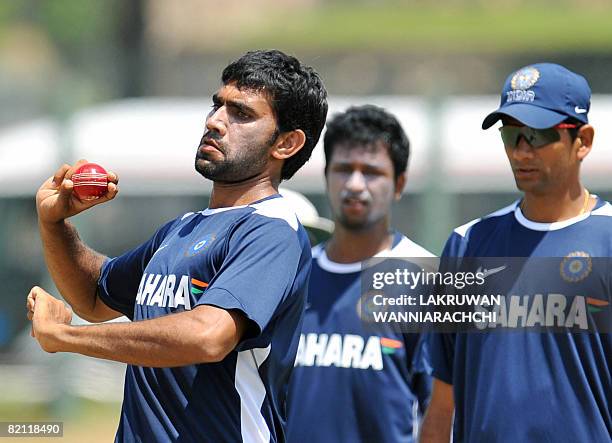 Indian cricketer Munaf Patel is watched by Indian cricket bowling coach Venkatesh Prasad and teammate Pragyan Ojha as he delivers a ball during a...