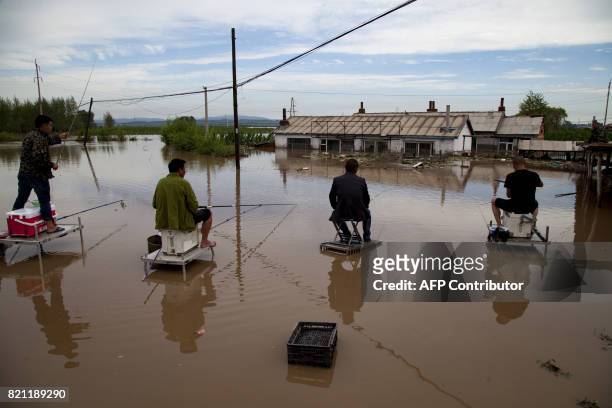 In this photograph taken on July 22 people fish in a flooded yard after heavy rains near Jilin city, in China's northeast Jilin province. The rains...