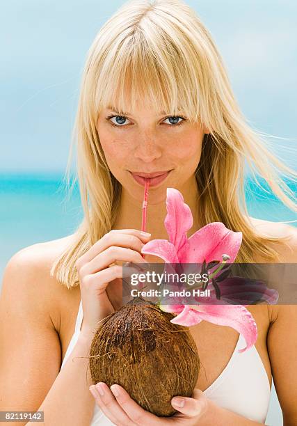 young woman drinking through a straw from coconut - coconut beach woman stock pictures, royalty-free photos & images