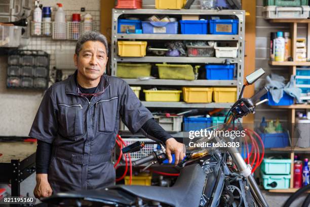 senior male mechanic in his motorcycle repair shop - motorcycle mechanic stock pictures, royalty-free photos & images