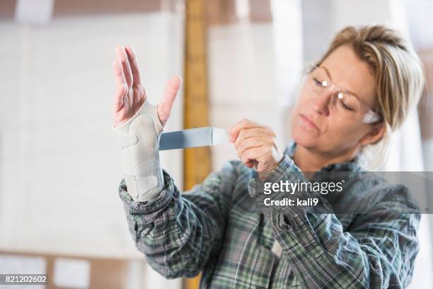 kvinna som arbetar i fabriken att sätta stag på handleden - karpaltunnelsyndrom bildbanksfoton och bilder