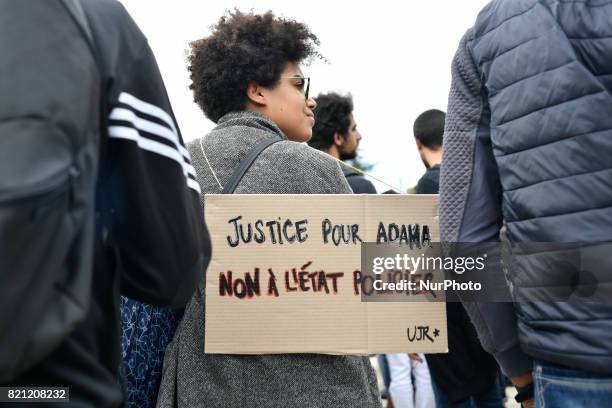 People raise their fists as they take part in a march in memory of Adama Traore, who died during his arrest by the police in July 2016, on July 22,...