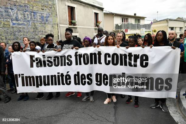 People raise their fists as they take part in a march in memory of Adama Traore, who died during his arrest by the police in July 2016, on July 22,...