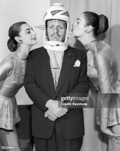 English comic actor Terry-Thomas poses with 'Venusiettes' Jenny Cornish and Jill Gladman, whilst preparing for his act at the Flying Saucer Ball in...