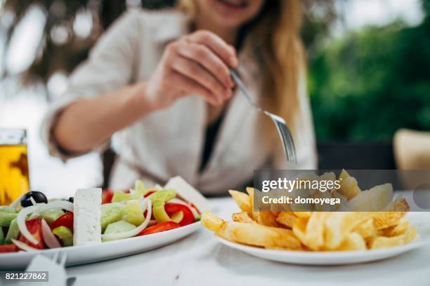 young beautiful tourist eating mediterranean food in the greek restaurant - beach bowl stock pictures, royalty-free photos & images