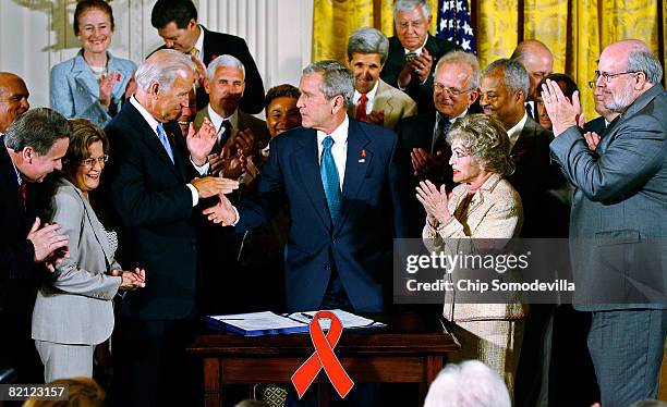 President George W. Bush shakes hands with Sen. Joe Biden while surrounded by members of Congress and guests after signing the United States Global...