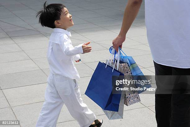 mid adult man walking with his son and carrying shopping bags - singapore shopping family stockfoto's en -beelden