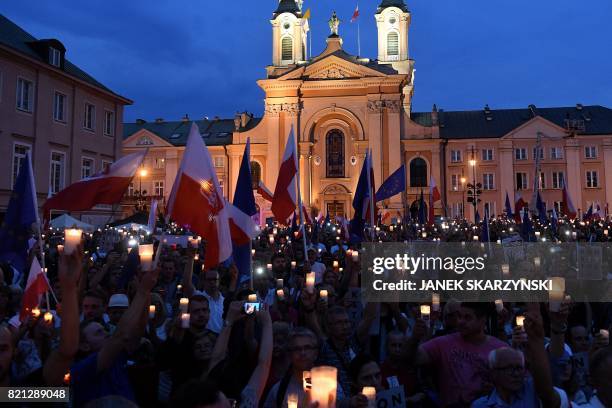 People hold candles and Polish national flags as they take part in demonstration in front of the Polish Supreme Court on July 23, 2017 in Warsaw to...