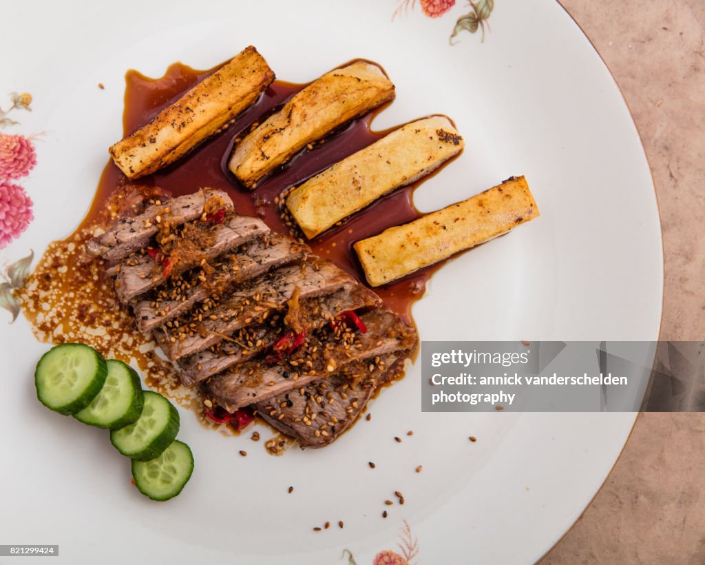 Sliced fried steak dish with soy-ginger sauce.