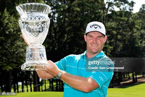 Grayson Murray of the United States celebrates with the trophy after winning on the 18th green during the final round of the Barbasol Championship at...