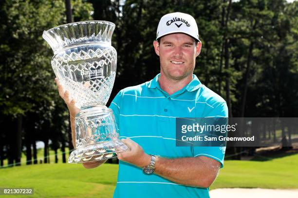 Grayson Murray of the United States celebrates with the trophy after winning on the 18th green during the final round of the Barbasol Championship at...