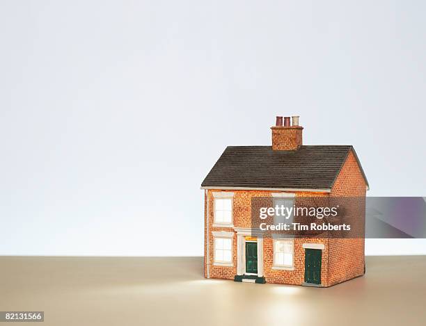 illuminated model house against blue background - spielzeughaus stock-fotos und bilder