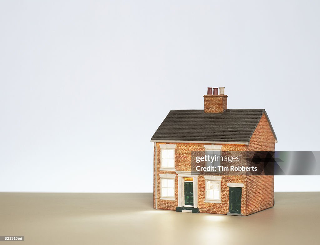 Illuminated model house against blue background