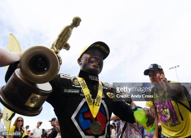 Top fuel driver Antron Brown celebrates with fans on his way up to the stage after winning the 38th annual NHRA Mopar Mile High Nationals at...