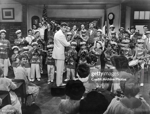 Robert Preston conducts a band recital for Shirley Jones and others, in the Warner Brothers musical comedy 'The Music Man' , 1962.