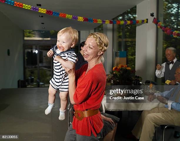 mother holding baby in arms laughing - messy house after party bildbanksfoton och bilder