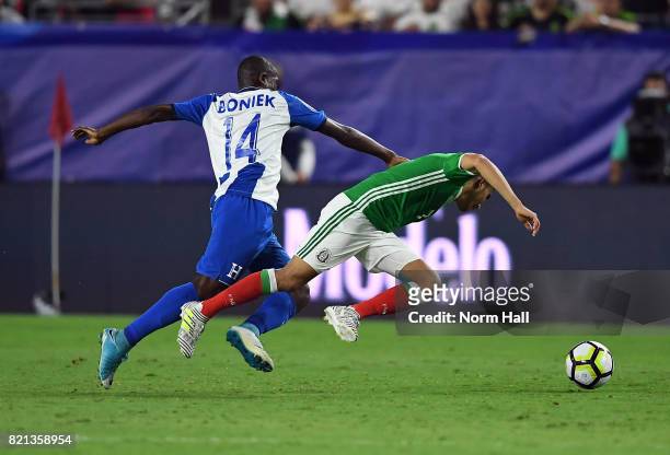 Orbelin Pineda of Mexico is pushed down from behind by Oscar Boniek Garcia of Honduras in a quarterfinal match during the CONCACAF Gold Cup at...