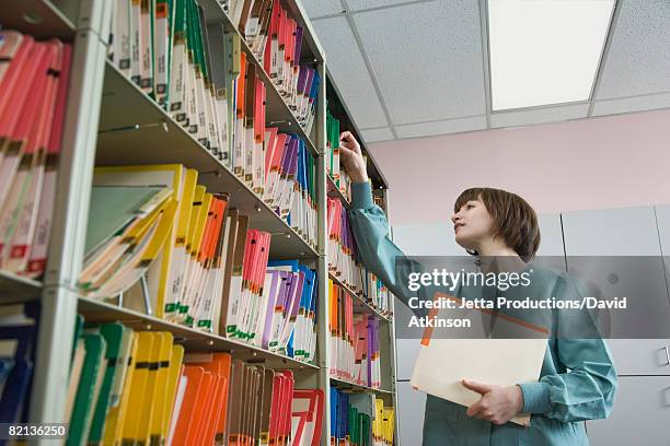 female doctor looking at charts - doctor reaching stock pictures, royalty-free photos & images