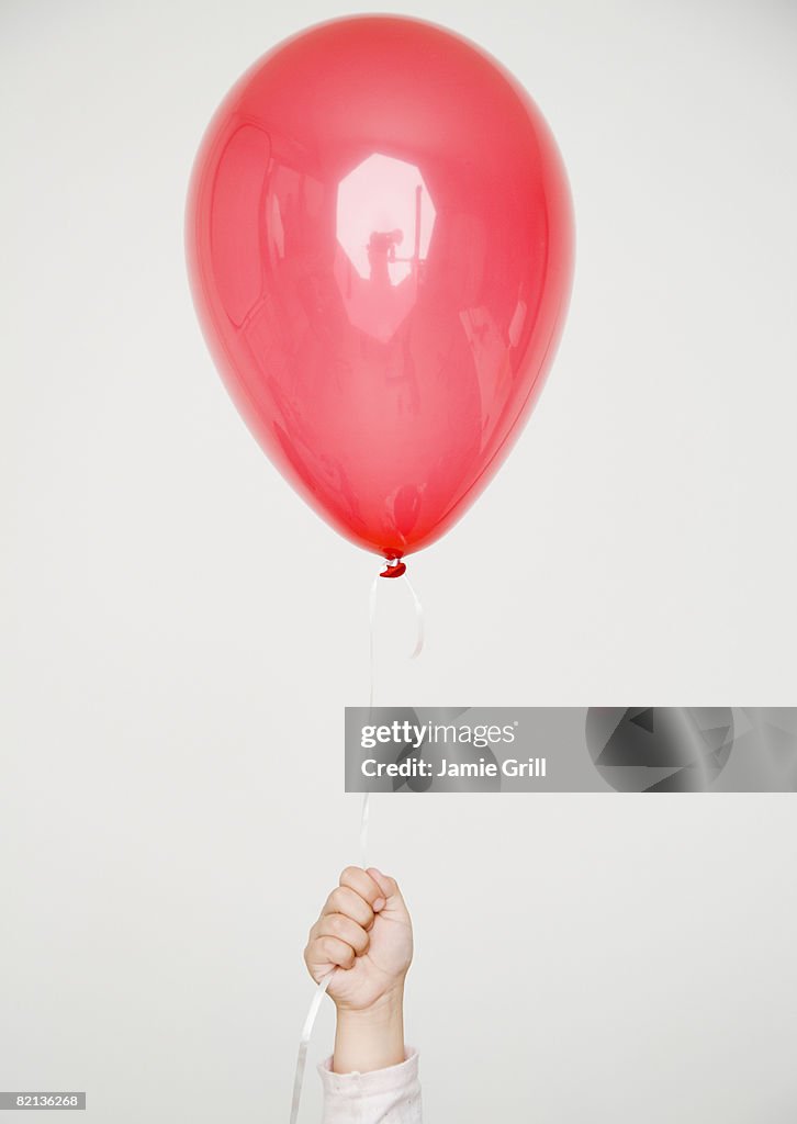 Child holding red balloon